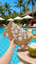 White floral embroidered jute fringe clutch with straw trim, poolside lifestyle shot