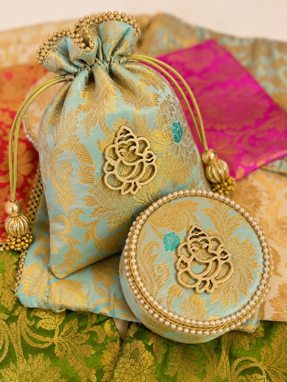 Aqua Banarasi brocade potli and matching round box with gold Ganesha motif, Sache wedding return gift set