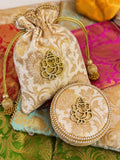Ivory Banarasi brocade potli and matching pearl-trimmed round box with gold Ganesha motif, a Sache Navratri return gift set