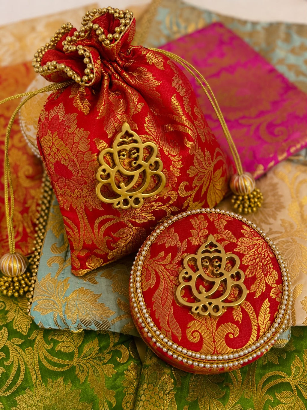 Red Banarasi brocade potli and pearl-trimmed box combo with gold Ganesha motif, Sache festive return gift