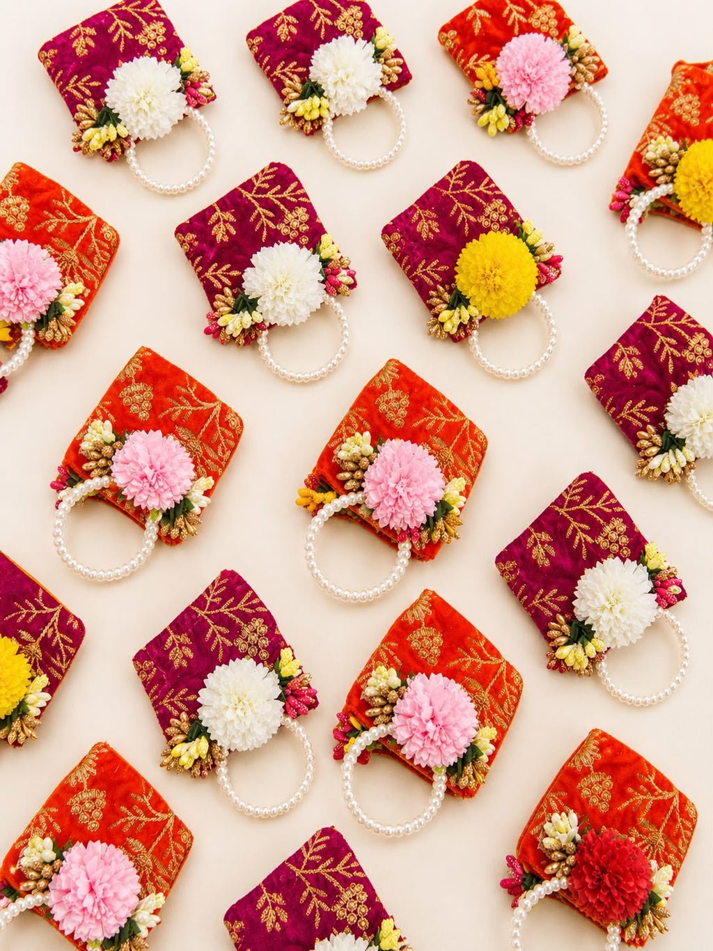 Velvet zari coin potlis in orange and rani pink laid out in a grid, bulk Navratri and Golu return gifts by Sache