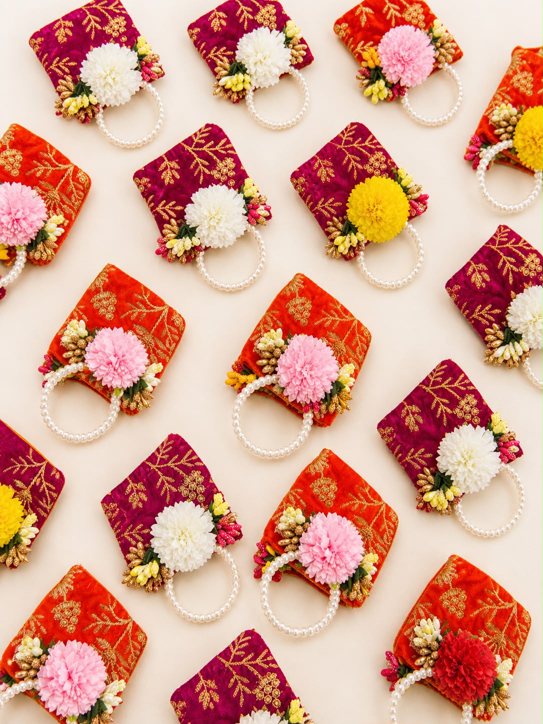 Velvet zari coin potlis in orange and rani pink laid out in a grid, bulk Navratri and Golu return gifts by Sache