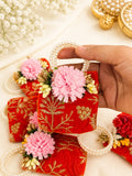 Orange velvet coin potli with gold zari embroidery, pink fabric flower and pearl beaded handle, a Sache Navratri return gift